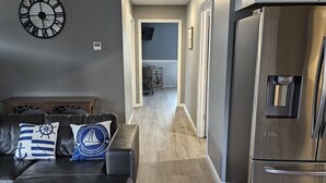 Een moderne keuken met een roestvrijstalen koelkast, een houten plafond en een gang naar een eetgedeelte.