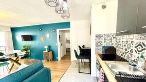 A modern kitchen with patterned tiles, a dining area with a blue sofa, and a TV mounted on the wall. - 35m2# Luxe#chateau#insead#bestodblo (Fontainebleau)