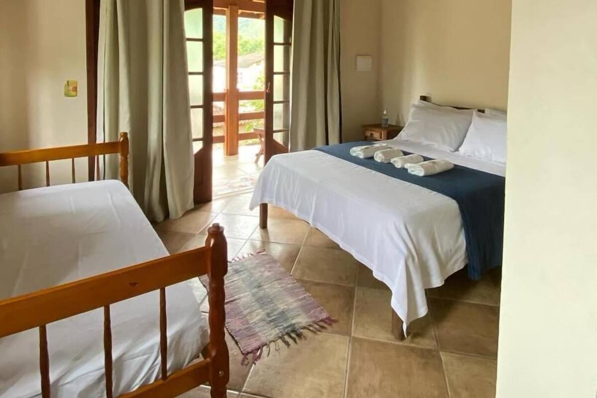 A room with two beds, a wooden ceiling, and a view through a door.