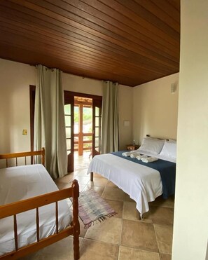 Una habitación con dos camas, techo de madera y vista por una puerta.