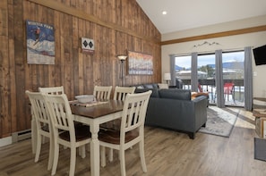 Un área de comedor con pared de madera, un sofá y vistas al exterior.