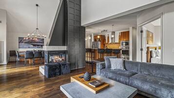 Un salón moderno con chimenea, un sofá gris y un comedor con vistas a la cocina.