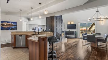 Una cocina moderna con una isla central, taburetes de bar y un comedor con una mesa grande y sillas.