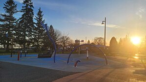A park with a sign reading "Port Darlington," benches, and a sunset in the background.