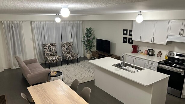 Een moderne keuken met een centraal eiland, witte kasten en een eetgedeelte met een houten tafel en stoelen.