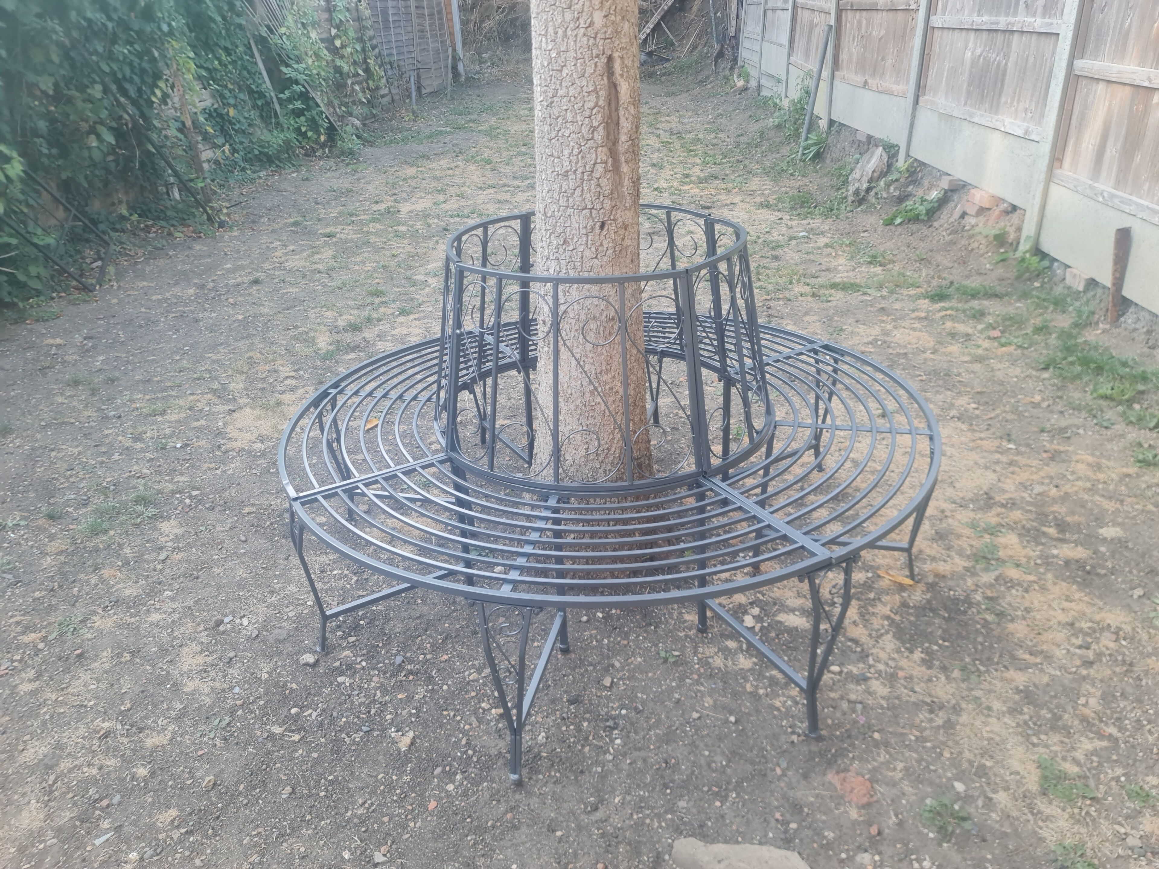 A tree surrounded by a circular metal bench structure.
