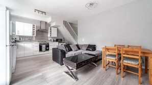 Eine moderne Küche mit weißen Schränken, einem eingebauten Backofen und einer Treppe zu einem Erkerraum.
