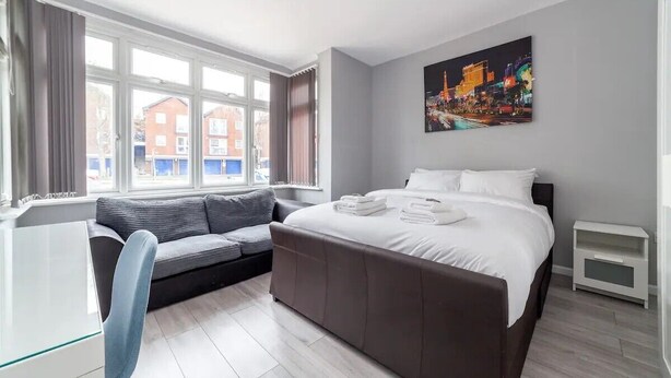 Ein modernes Hotelzimmer mit einem großen Bett, einer Sitzecke, einem Schreibtisch und einem Fenster mit Blick auf die Stadt.