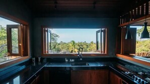 Una cucina con un'ampia finestra, mobili in legno e un piano di lavoro nero.