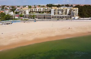 A coastal area with a sandy beach, a promenade, and a row of multi-story buildings in the background. - Oceanview 4 U - Close to Lisbon! (Oeiras)