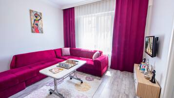 A modern living room with a pink sofa, a coffee table with a chess set, and a small wooden side table with figurines.