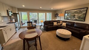 A modern living room with a sectional sofa, a dining table with chairs, and a kitchen area with cabinets and appliances. - Enjoy all the comforts of home in a safe, wooded area of NE Seattle, close to UW (Seattle)