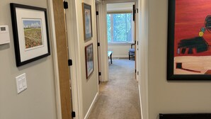 A hallway with framed artwork on the walls, a bench, and a door leading to another room. - Enjoy all the comforts of home in a safe, wooded area of NE Seattle, close to UW (Seattle)
