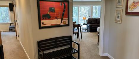A modern living room with a black bench, a painting, and a sofa.