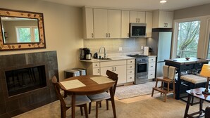 A modern kitchen with white cabinets, a built-in microwave, and a gas stove. There is a dining table with chairs and a fireplace. - Enjoy all the comforts of home in a safe, wooded area of NE Seattle, close to UW (Seattle)