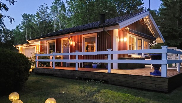 A wooden cabin with a white porch, a covered deck, and a large window overlooking the deck. - Gorgeous home in örkelljunga with WiFi (Örkelljunga)