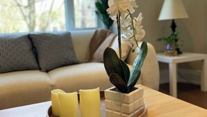 A cozy living room with a wooden coffee table holding candles and an orchid plant. - Cozy House,  cottage style in midtown Toronto. Great for Family. Pet friendly  (Toronto)