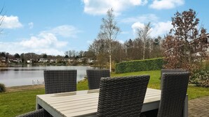Une table avec quatre chaises, une vue sur un lac et des maisons en arrière-plan.