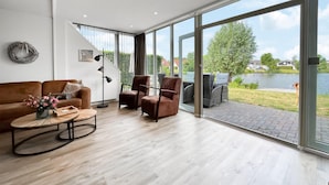 Un salon moderne doté d’une grande porte-fenêtre coulissante donnant sur une terrasse aménagée avec du mobilier d’extérieur.