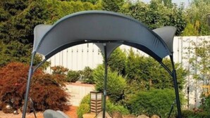 A corner swing chair with a canopy, set in a garden with a white fence and greenery in the background. - Maison Avec Terrasse (Fesches-le-Châtel)