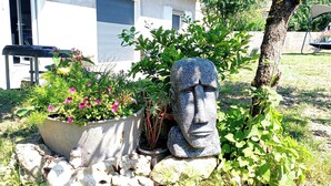 A garden with a stone statue, potted plants, and a concrete planter. - Maison Avec Terrasse (Fesches-le-Châtel)