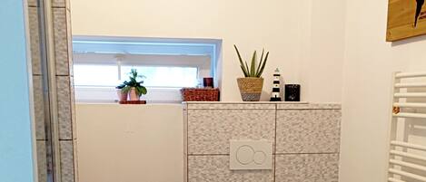 A compact bathroom with a toilet, a washing machine, and a small window.