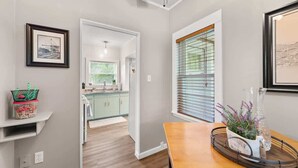 Una cocina moderna con armarios verde claro, encimera de madera y una ventana con persianas.
