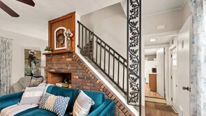 Una sala de estar con un sofá color turquesa, una chimenea de ladrillo y una escalera con barandilla negra.