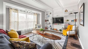 A modern living room with a sofa, coffee table, and TV. - Double the Space for Large Groups! Entire Duplex! (Cleveland)