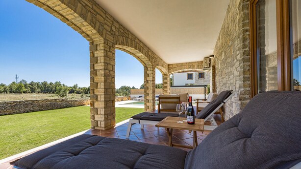 A covered outdoor seating area with stone pillars, a pool, and a view of the countryside. - Nice home in Cabrunici (Cabrunici)