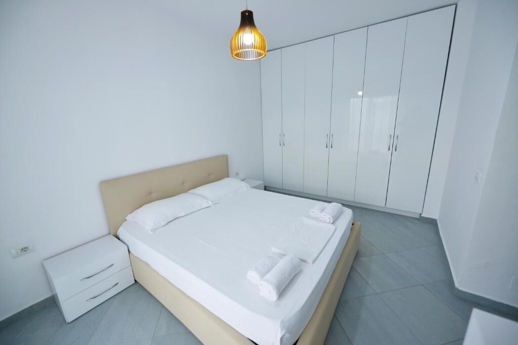 A modern bedroom with a bed, white wardrobe, and a bedside table.