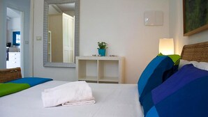 Une chambre d’hôtel avec un lit, un miroir, une table de chevet avec une plante, une lampe et un tableau au mur.