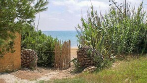 Une entrée de plage agrémentée d’un portail en bois, d’un mur de pierre et d’un sentier menant à la mer.