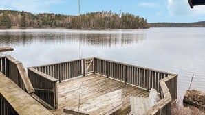 A wooden dock extending over calm water with a forested island in the background. - Cozy home in Fjärås with house sea view (Fjärås)