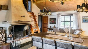 A cozy interior with a fireplace, wooden staircase, dining area, and a large window with curtains. - Cozy home in Fjärås with house sea view (Fjärås)