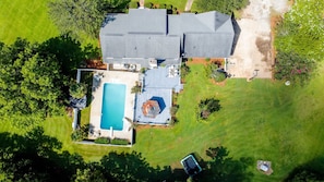 An aerial view of a house with a large backyard, a swimming pool, and a hot tub.