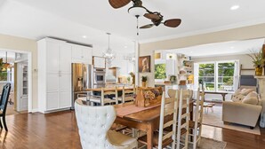 A spacious kitchen with white cabinetry, a wooden dining table, and a ceiling fan.