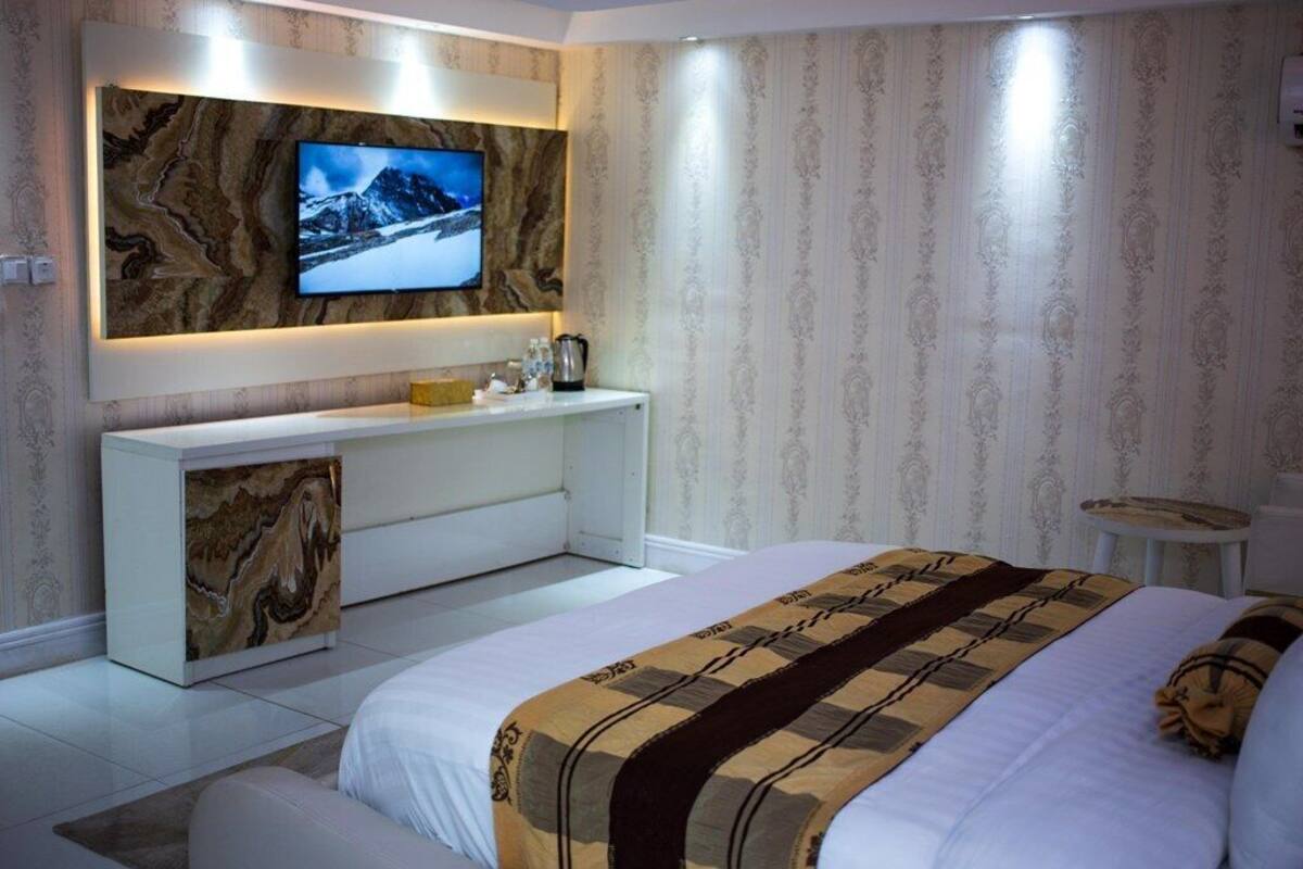Ein modernes Schlafzimmer mit einem großen Bett, einem an der Wand montierten Fernseher, einem Konsolentisch und einem kleinen runden Tisch.