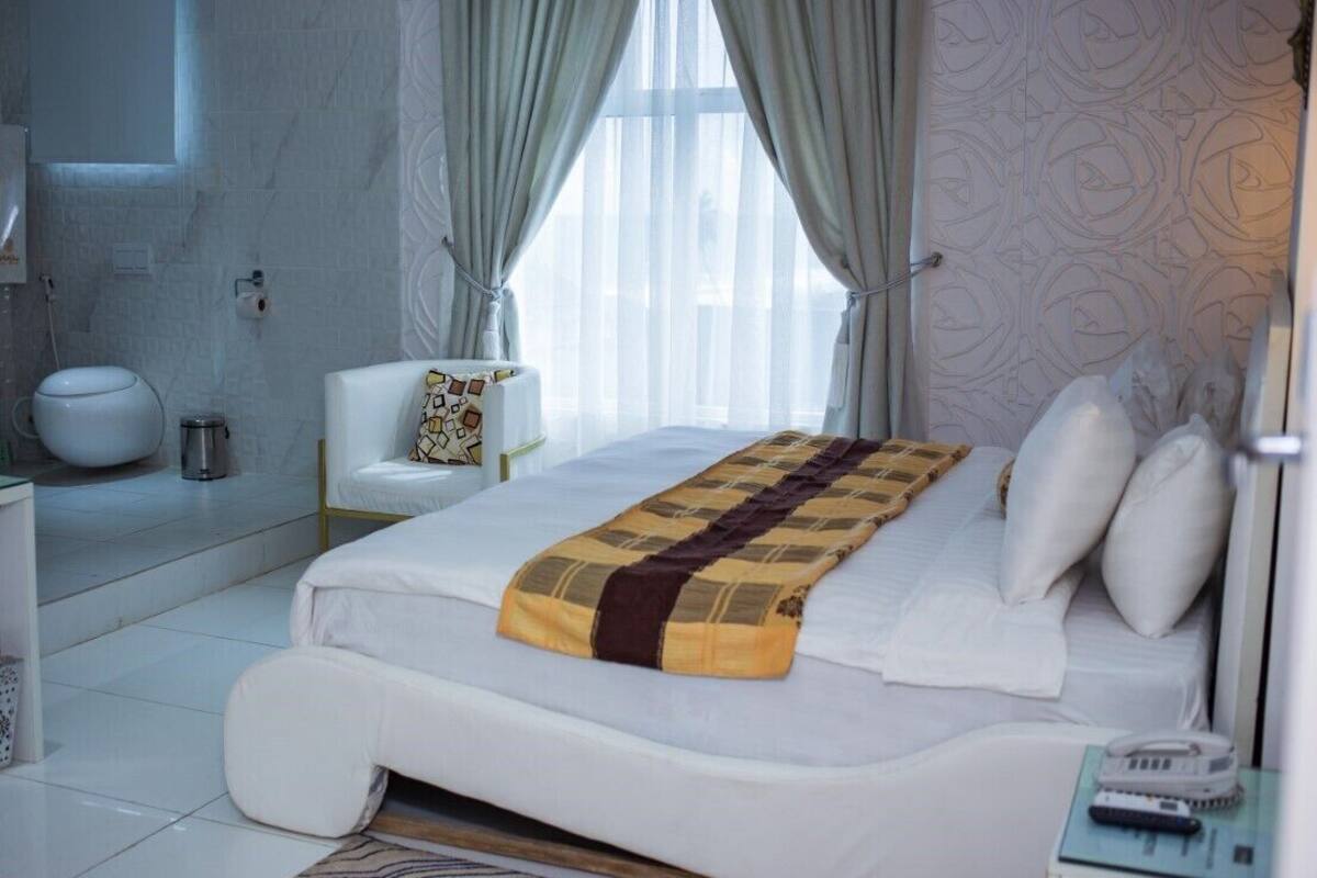 Ein Hotelzimmer mit Bett, Sessel, Nachttisch und Bad.