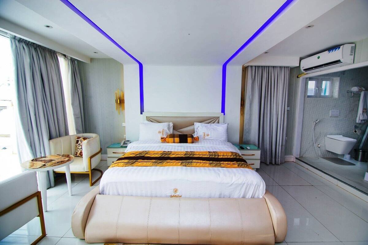 Ein modernes Hotelzimmer mit einem großen Bett, Nachttischen, einer Sitzecke und einem Badezimmer.
