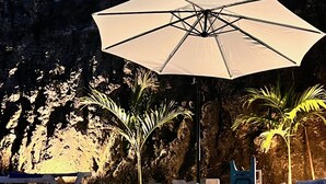 A swimming pool with a concrete edge, a large umbrella, and palm trees in the background. - 	
Romantic Spanish apto w/Infinity Pool  (Las Terrenas)