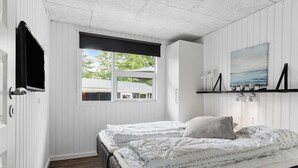 A bedroom with two beds, a window with a view of a house, a painting on the wall, and a shelf with decorative items. - Beautiful home in Hejls with WiFi (Hejls)