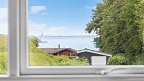 A view through a window of a house with a garage, a red building, and a large tree. - Beautiful home in Hejls with WiFi (Hejls)