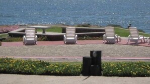 Vista costera con una zona de estar que incluye sillones reclinables y una mesa, con vista al mar.