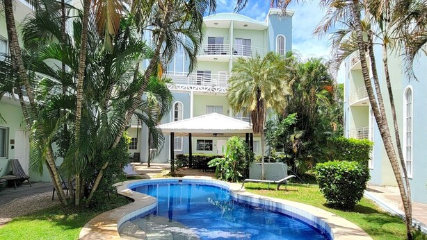Une piscine entourée de palmiers et un bâtiment doté de balcons.