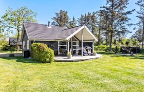 Une maison dotée d’un patio couvert, d’un espace barbecue et d’une pelouse.