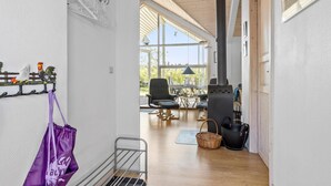 A hallway with a wooden floor, a metal rack with hangers, a purple bag, and a metal chair. - 3 bedroom amazing home in Vestervig (Vestervig)