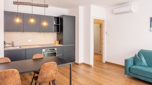 Une cuisine moderne avec des meubles gris, un plan de travail noir et trois suspensions lumineuses.
