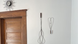 A wooden door, a wall-mounted sunburst clock, a whisk, a whisk holder, and a vintage-style cart with a pitcher and cup. - The Adolphus - 4 Bedrooms, 2 Baths. Sleeps 8 comfortably!  (Oak Harbor)