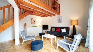 A modern living room with a staircase, a sofa set, a coffee table, and a TV. - Capbreton Villa au Domaine de la Cigalière Pour 4 Personnes (CAPBRETON)